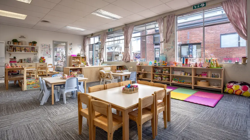 Spotless clean bright Australian childcare centre playroom with small tables, chairs and toys neatly arranged